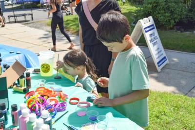 Joel, 8, and Lilia, 3, paint rocks at a craft station. 