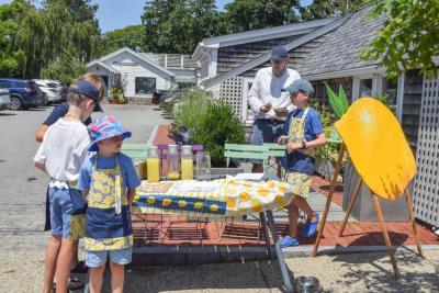 Some boys work a lemonade stand. 