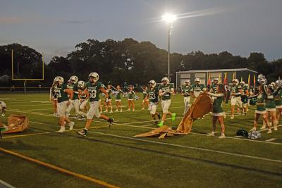 The football players running through the banner. 