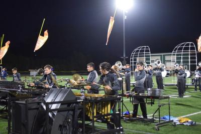 The drum section performs while flags fly behind them. 
