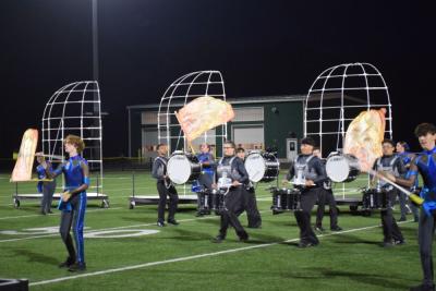 The color guard in front of the drumline. 