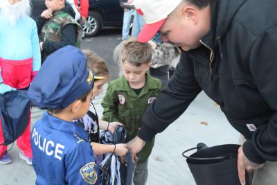 A firefighter hands out candy to some trick or treaters. 