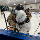 Opposing players wrestle against the glass. 