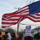 An American flag waves over a sign against I.C.E. Photos by Kat Sheridan