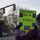 A sign calling for action held up to the road.