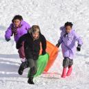 Quincy and Veida Teixeira and Londyn Acevedo, all 9, run back up the hill to sled down again.