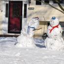 A couple of decked out snowmen hang out.