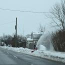 A resident snow-blows the sidewalk.
