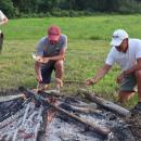 Two men find the best way to roast the hot dogs. 