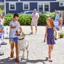 Two kids walk Rosie the lab. 
