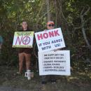 A woman holds a sign explaining why the residents of Old Fall River Road do not support the shared use path. 