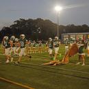 The football players running through the banner. 