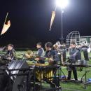 The drum section performs while flags fly behind them. 