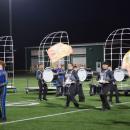 The color guard in front of the drumline. 