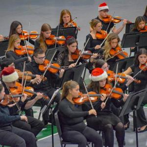 The orchestra students perform while dressed for Christmas.