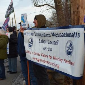 A labor organization holds their sign.
