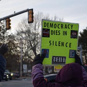 A sign calling for action held up to the road.