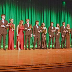 The entire cast pose in the formal wear at the end of the show.