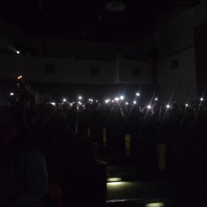 The crowd waves phone flashlights during a song.