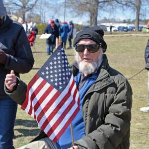 A man gives a thumbs up while holding the American flag.