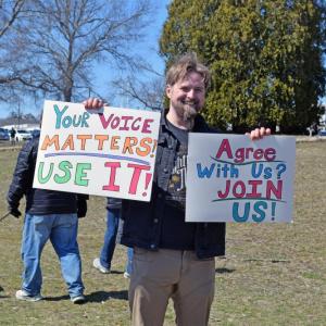 A man holds signs urging people to join.