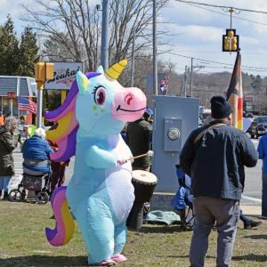 The rainbow unicorn for peace plays a drum.