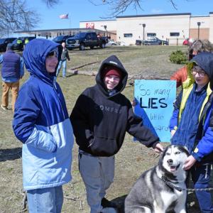 Some kids pet a dog at the protest.