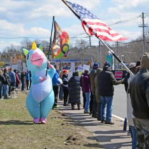 The rainbow unicorn for peace waves her peace flag.