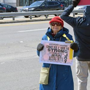 A woman shows her sign asking for joyful protest.