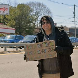 A man shows his sign calling for community.