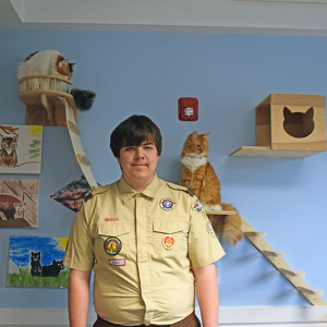 Zane Moriarty poses with the cat wall he helped build. 