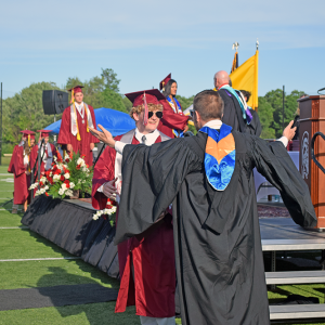 A student and a member of staff celebrate after the student received his diploma. 