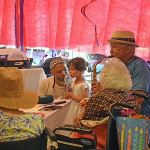 Gene Monteiro plays the saxophone for his aunt, while his granddaughter 'plays' alone. 