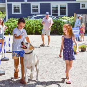 Two kids walk Rosie the lab. 