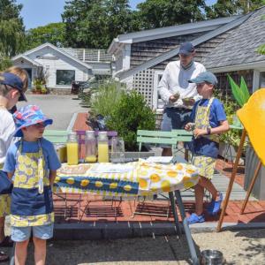 Some boys work a lemonade stand. 