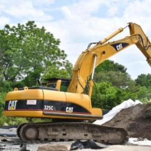 An excavator near a pile of contaminated soil at the former staging site on McCabe Street. Photo by Chris Shea