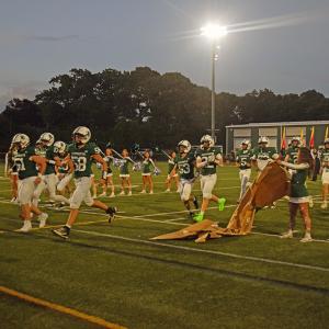 The football players running through the banner. 