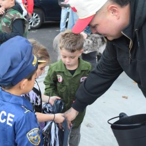A firefighter hands out candy to some trick or treaters. 